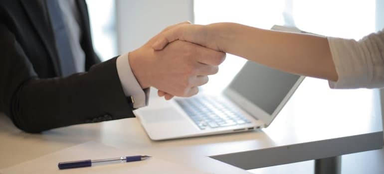 Two people shaking jands upon signing a moving contract