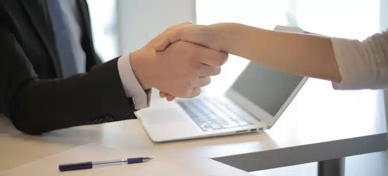 Two people shaking jands upon signing a moving contract