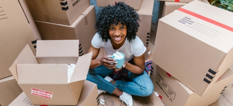 a woman smiling surrounded by boxes when moving partially