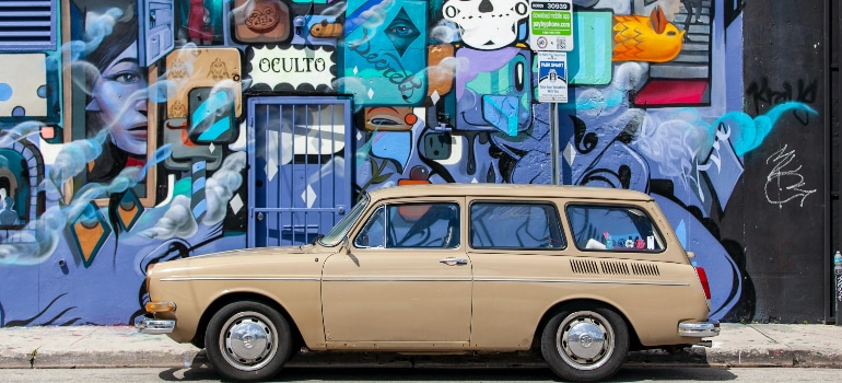 Classic car by colorful Wynwood mural, showing the art scene that inspires people to move to Wynwood in 2025.