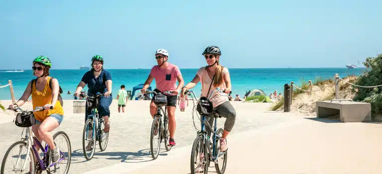 Cyclists riding a beachside path with turquoise water at top outdoor exercise parks in Miami.