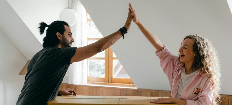 Couple celebrating with a high five after unpacking boxes in their new home.