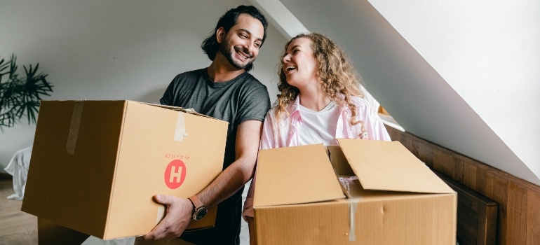 Happy couple moving boxes into their new space, reminding us of the joy in Best places in FL for first-time homebuyers.