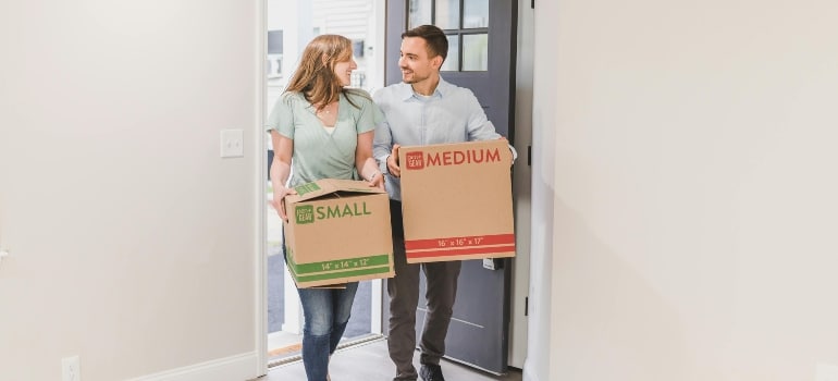 Couple walking into their home with moving boxes, feeling the excitement of settling into the Best places in FL for first-time homebuyers.