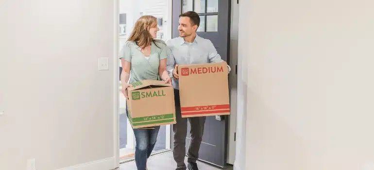 Couple walking into their home with moving boxes, feeling the excitement of settling into the Best places in FL for first-time homebuyers.