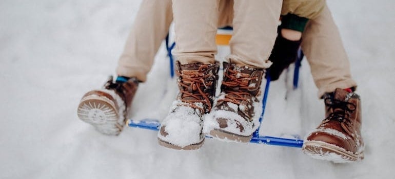 Two Boys on a Sleigh with boots covered with snow