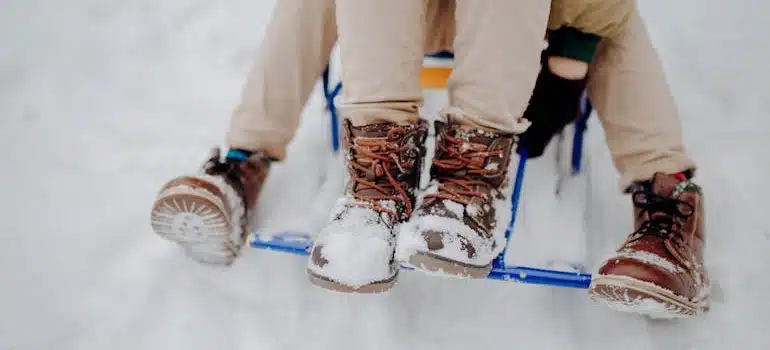 Two Boys on a Sleigh with boots covered with snow