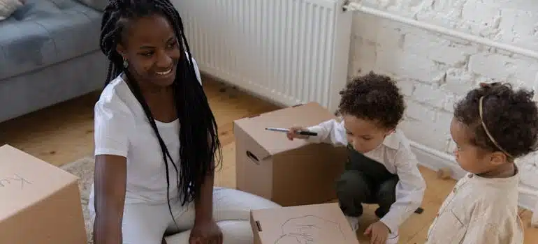 Family Labeling Cardboard Boxes Sitting on Floor