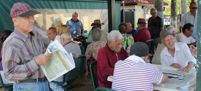 People Sitting at a Table Playing Dominoes in one of the senior-friendly neighborhoods in Miami