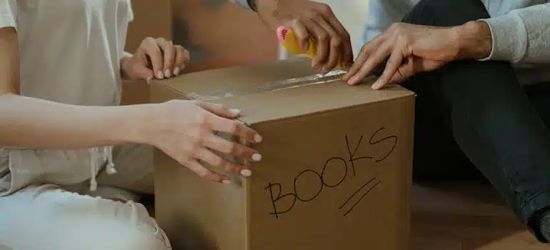 A couple packing books for moving in the rain